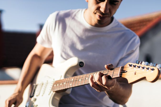 man playing electric guitar on a rooftop. close-up