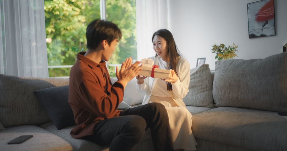 Boyfriend Surprising His Partner with Two Gifts Wrapped in Festive Design.