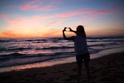 Female tourist posing on seaside at sunset