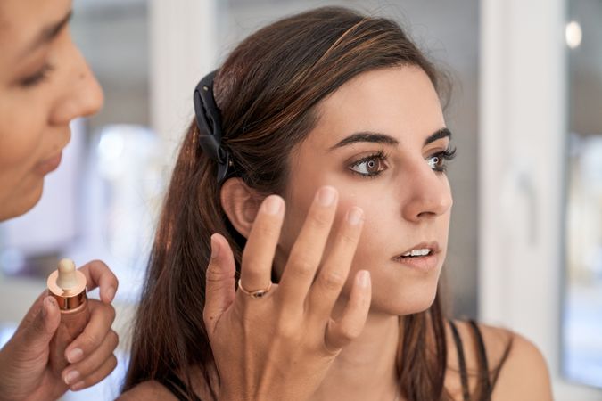 Makeup artist applying cosmetic product on model