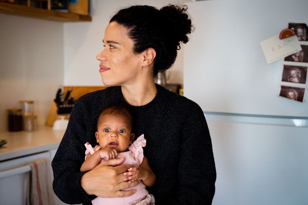 Smiling mother holding cute baby in kitchen