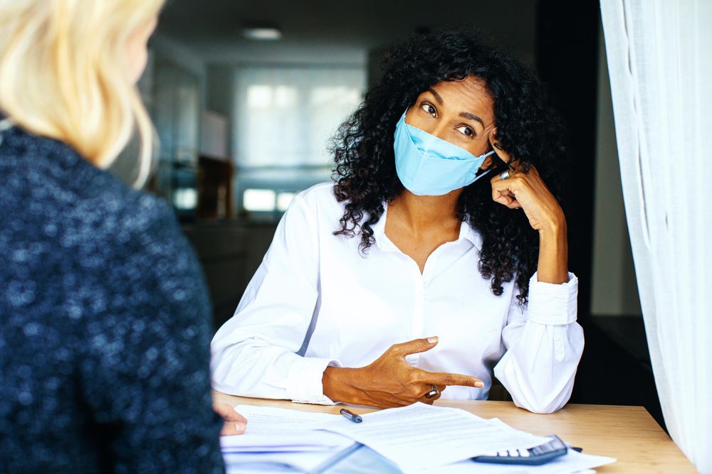 Two colleagues working through a challenge at work discussion while wearing facemasks