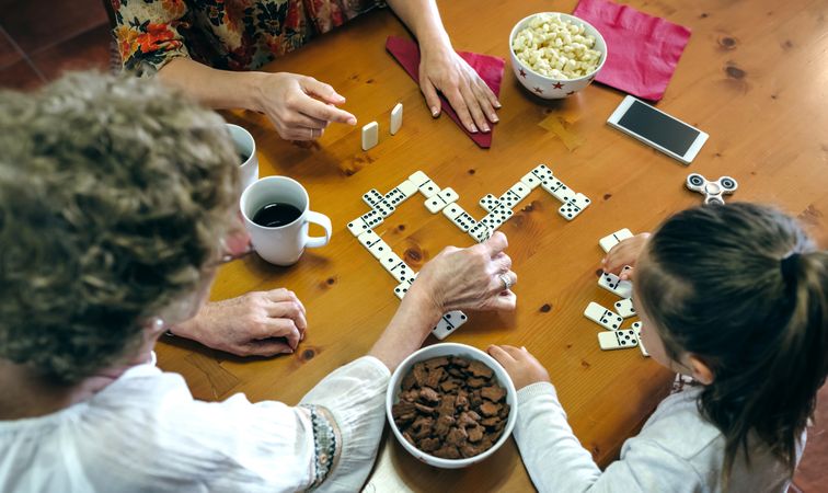 Top view of three female generations playing domino