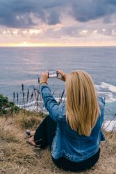 Female tourist taking shot of sea in twilight