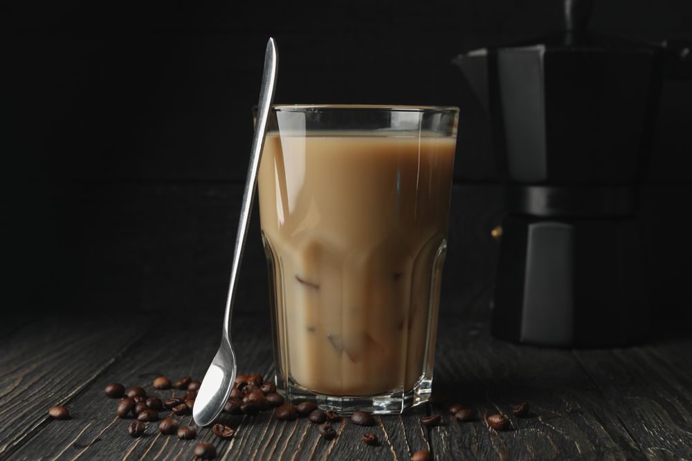 Composition with ice coffee and coffee seeds on wooden background