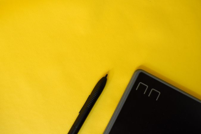 Stylus and corner of digital tablet on yellow table