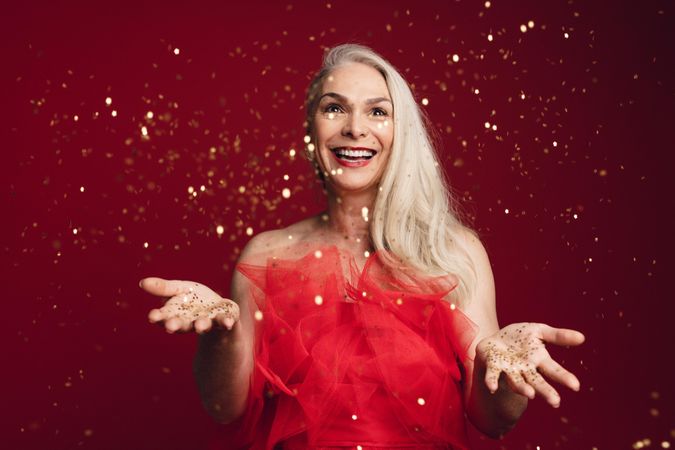 Excited woman throwing glitter in studio