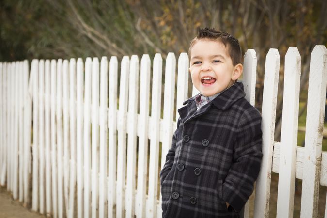 Young Boy Waiting For School Bus Along Fence