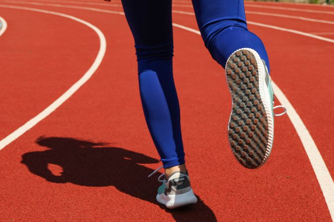 Girl running on red athletic track. Sport concept