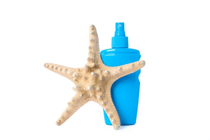Sunscreen spray with starfish isolated on studio background. Summer vacation accessories