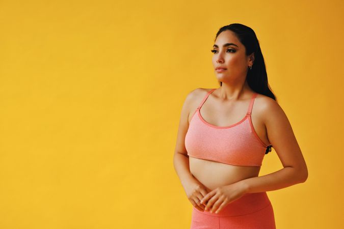 Hispanic woman in yoga clothes looking in the distance with copy space