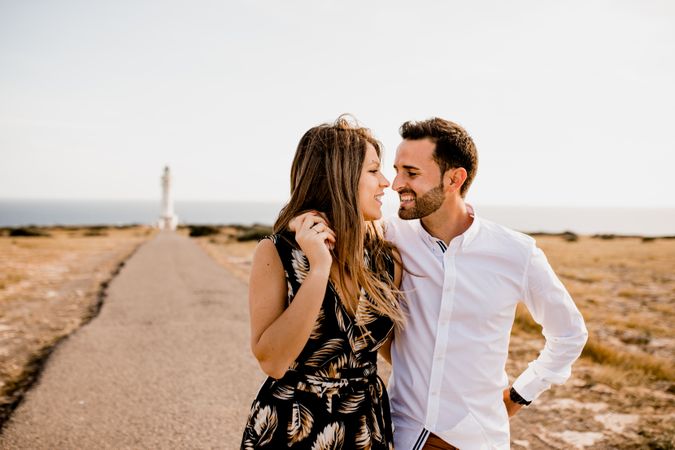 Smiling lovers cuddling on path to sea