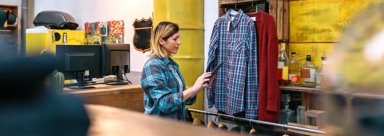 Banner of young woman looking digital tablet while checking stock on second hand clothing store