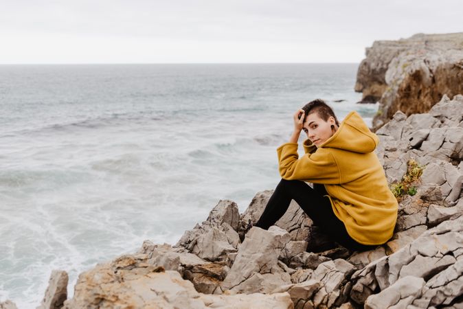 Woman in yellow hoodie on stony shore