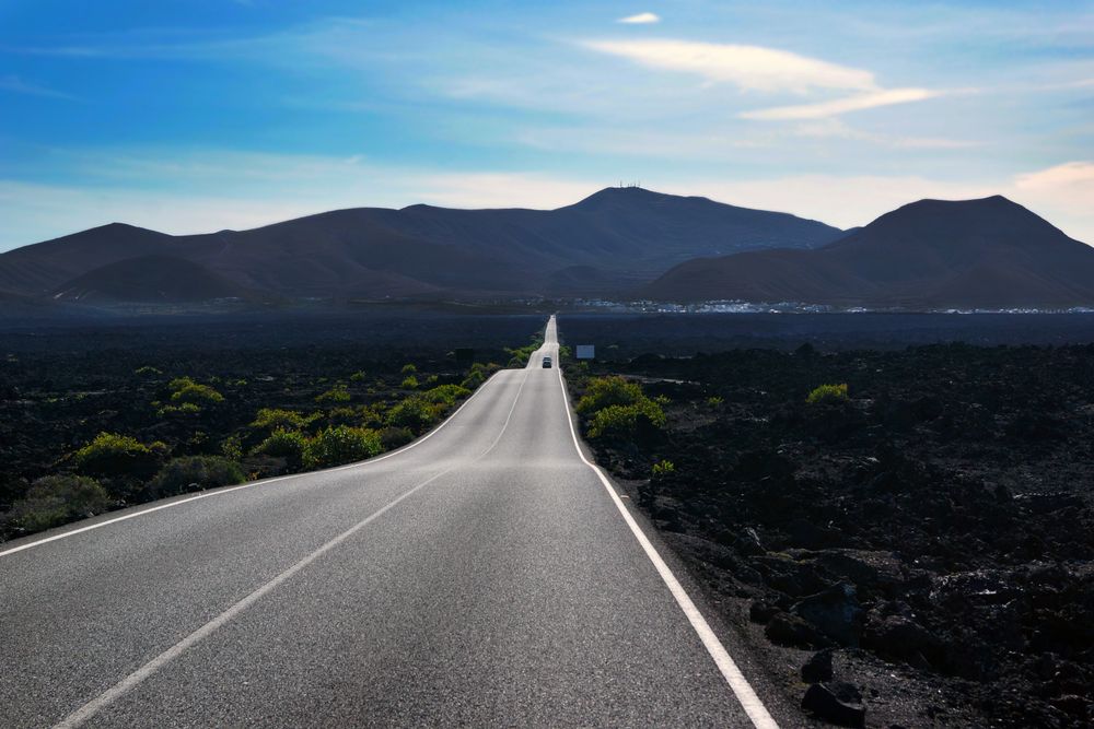 Endless road riding to mountains along fields