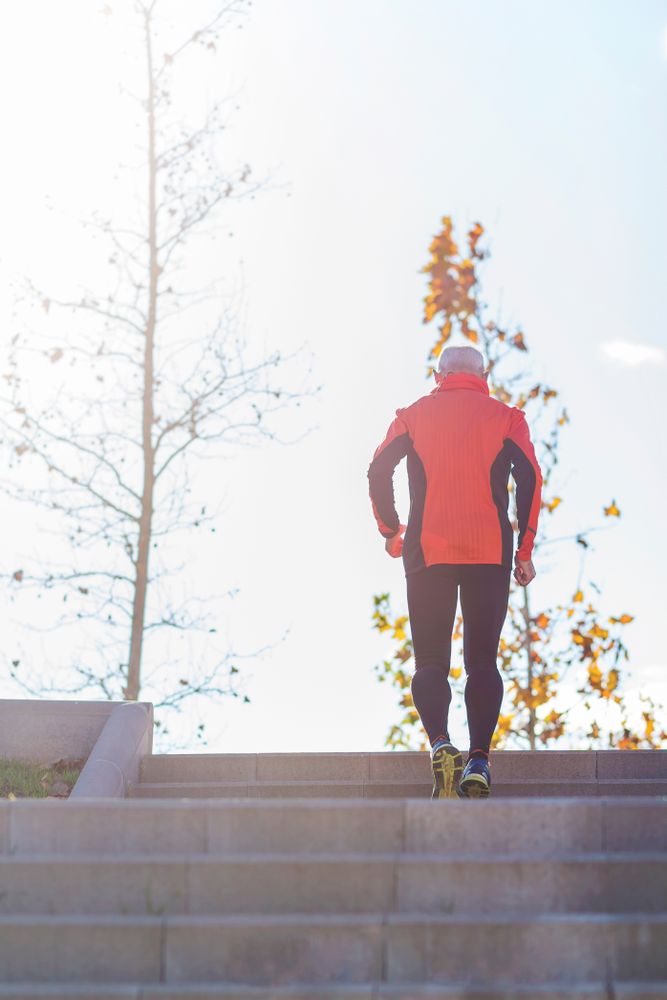 Man walking up cement stairs in park on fall day