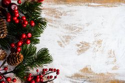 Christmas card concept of holly and pine cones on rustic background