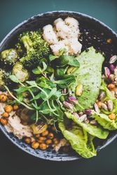 Healthy vegetarian bowl pictured on green surface, close up
