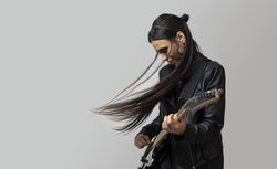 A young woman, rocker, enjoys playing the electric guitar, while dancing and her hair moving in the wind