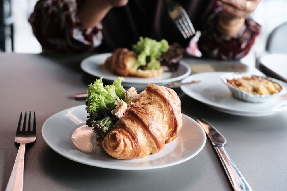 Croissant sandwich on table with person in background