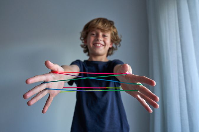 Smiling boy making string figures