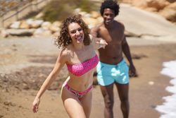 Woman leads man on sandy beach