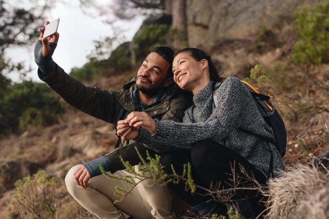 Couple out on hike in mountains taking selfie with smart phone