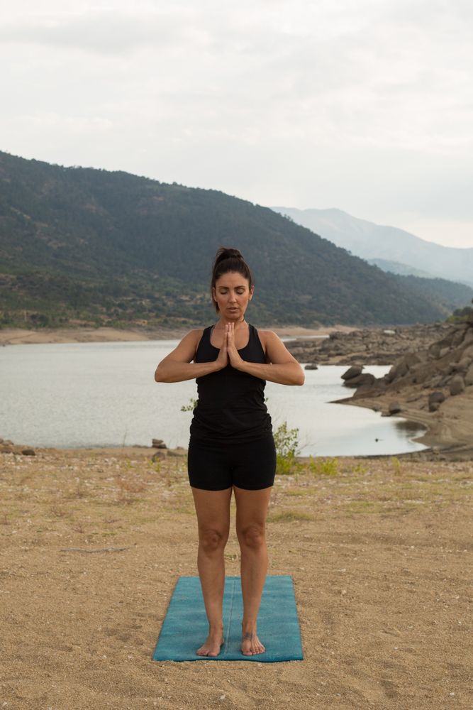 Woman practicing yoga outdoors near water