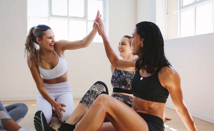 Accomplished women celebrating with high five after completing workout