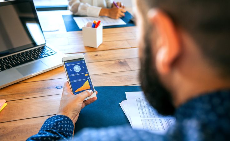 Businessman looking mobile with bitcoins information
