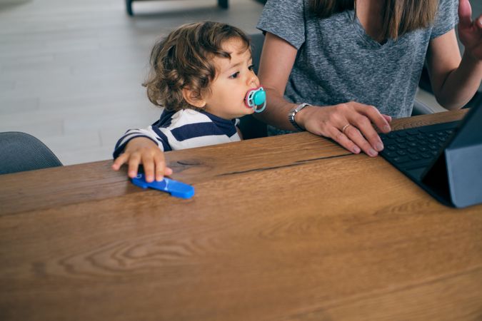 Mother and son sitting near table with tablet