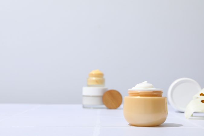 Jars with cream on gray background, space for text