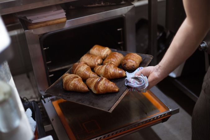 Baker with tray of fresh croissants