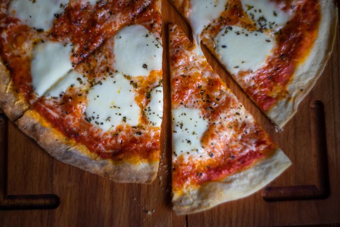 Top view of sliced cheese pizza on wooden board