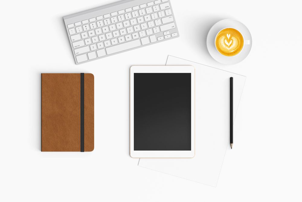 Modern workspace with coffee cup, paper, notebook and tablet copy space