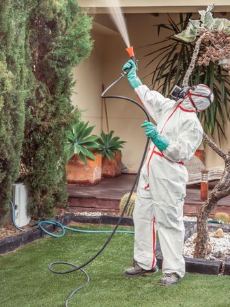 Fumigator in uniform spraying substance on garden