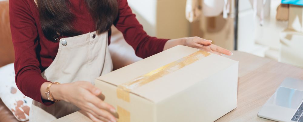 Asian woman sealing a box at home