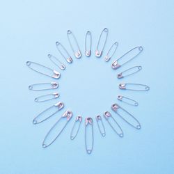 Safety pins in a circle shape over blue background