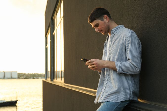 Young man uses a phone outdoor. Writing a message