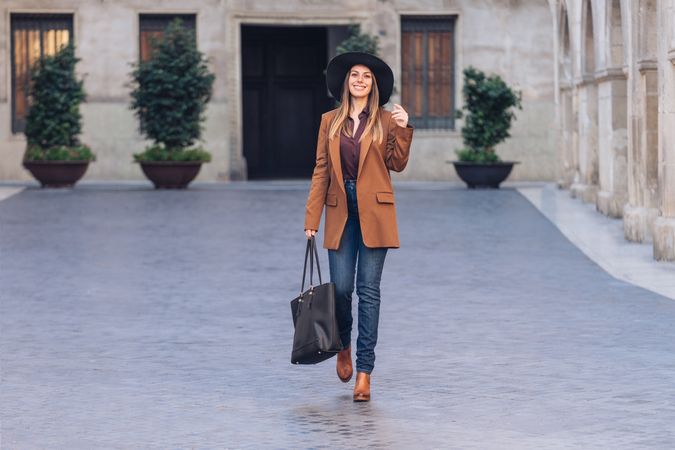 Gorgeous woman in fashionable outfit strolling on city street