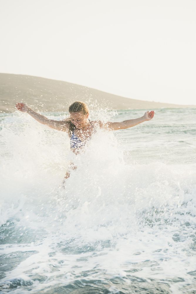 Woman with outstretched arms splashing in water at the beach