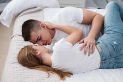 Passionate couple kissing on bed of bubble room