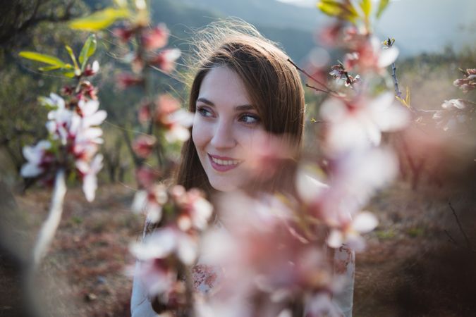 Young happy woman between trees in garden