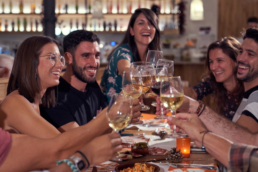 Positive group of friends clinking wineglasses in bar