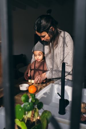 Young mother and little son cutting banana at table