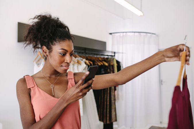 Black boutique owner taking picture of her new blouse design