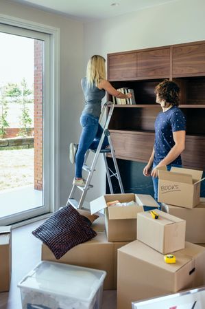 Couple unpacking boxes and placing books