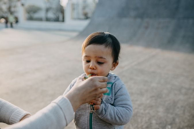 Toddler drinking from straw and woman is holding cup for him