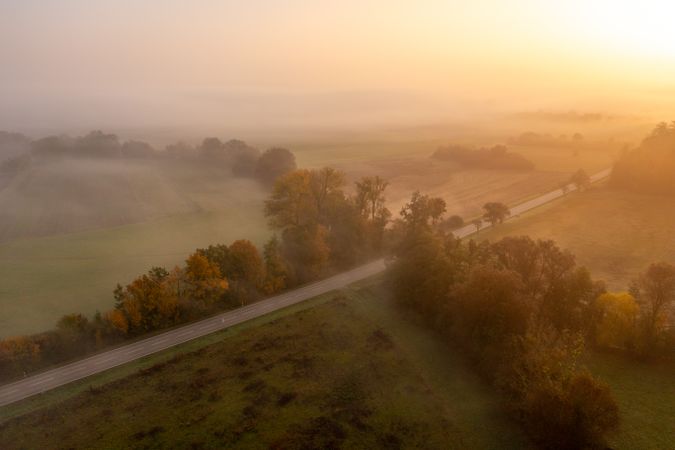 Drone aerial image with multicolored forest and a road on a foggy morning of autumn