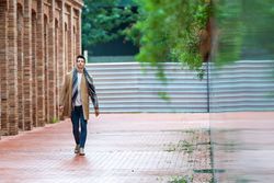 Portrait of young man in open fall coat walking down brick road
